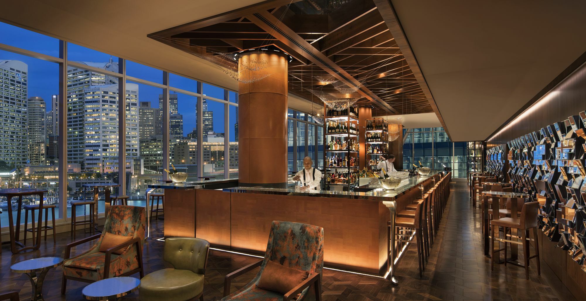 Sofitel Sydney Darling Harbour Hotel Exterior photo The photo depicts a stylish and modern bar interior, featuring a sleek design with a mix of warm lighting and contemporary elements. The bar is constructed from a polished material, likely wood or metal, and is stocked with various bottles of spirits