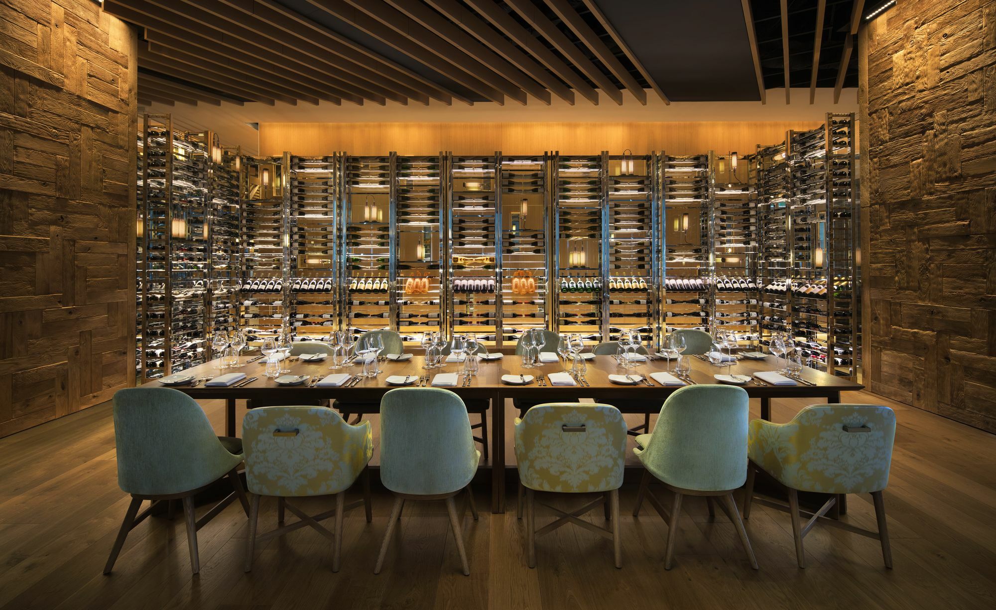 Sofitel Sydney Darling Harbour Hotel Exterior photo The photo shows a stylish dining area of a restaurant. In the foreground, there is a long dining table set with plates and utensils, ready for a meal. Surrounding the table are several light-colored chairs. In the background, there is a prominent win